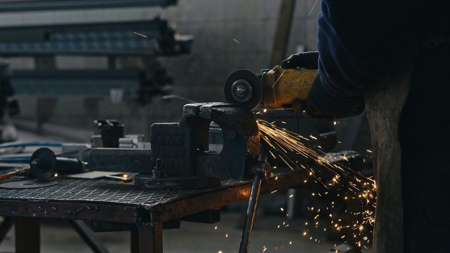 Metallbearbeitung mit Winkelschleifer in der Stahlwerkstatt, Funkenflug am Werkstück